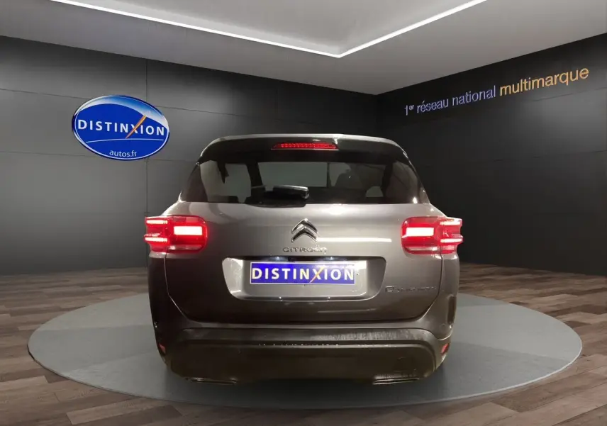 Vue arrière d'un Citroën C5 Aircross gris platinium 2023 avec feux arrière allumés en showroom.
