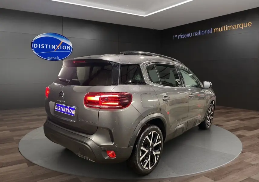 Vue 3/4 arrière droite d'un Citroën C5 Aircross gris platinium avec feux LED et jantes alliage noires.