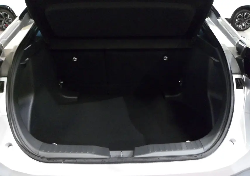 Coffre ouvert du Toyota C-HR hybride gris minéral, vue arrière montrant l'espace de chargement vide.