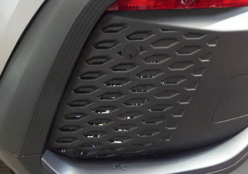 Gros plan sur la grille noire texturée du pare-chocs avant du Toyota C-HR Hybride 140 CH Style gris minéral 2025.
