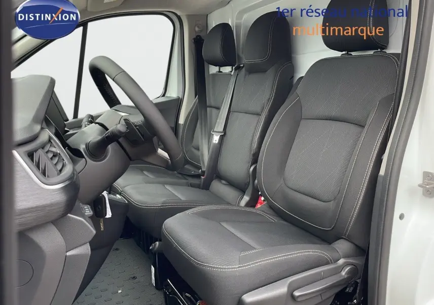 Vue intérieure côté conducteur du Renault Trafic Fourgon blanc glacier 2025, sièges noirs avec surpiqûres claires.