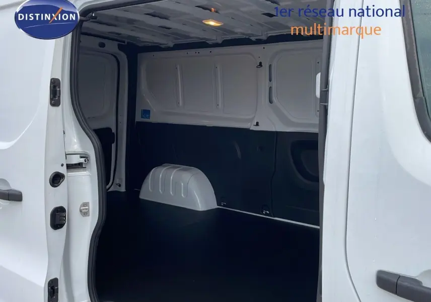 Vue intérieure du fourgon Renault Trafic blanc glacier L2H1, montrant l'espace de chargement vide et les portes latérales ouvertes.