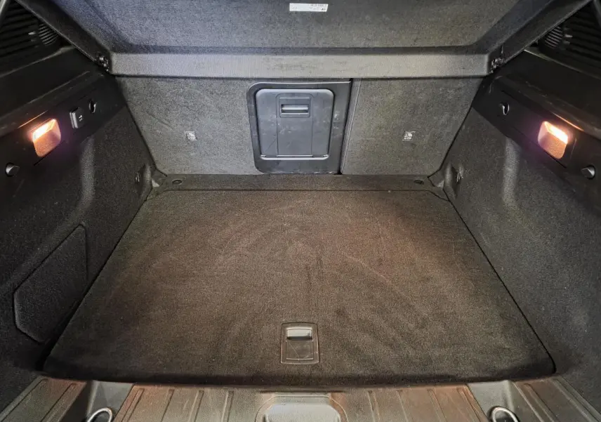 Coffre ouvert de l'Alfa Romeo Tonale 2025, vue intérieure montrant le tapis noir et l'éclairage latéral.