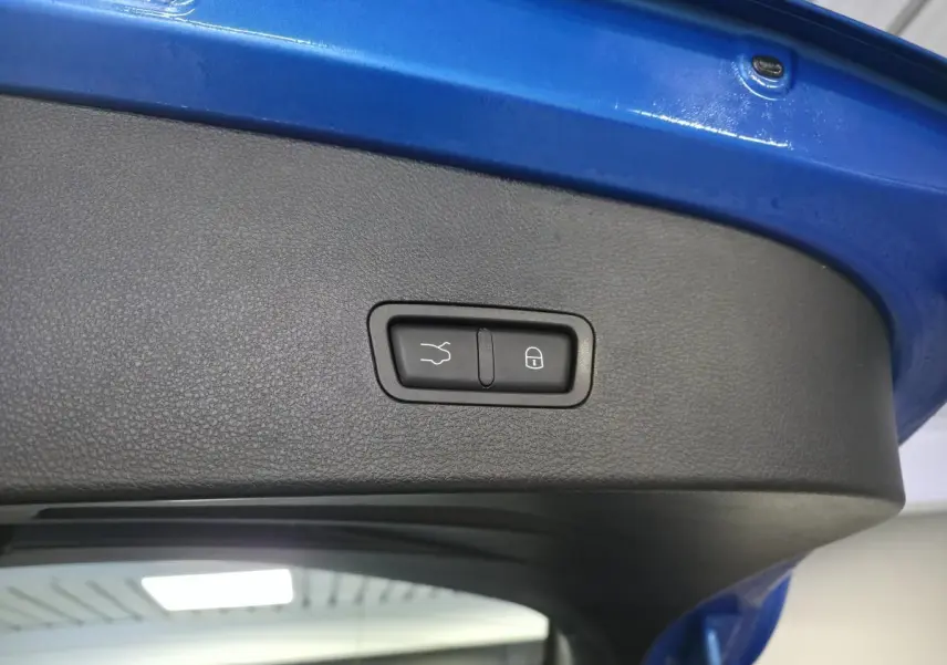 Gros plan sur le hayon électrique bleu de l'Alfa Romeo Tonale avec boutons de fermeture et verrouillage intégrés.