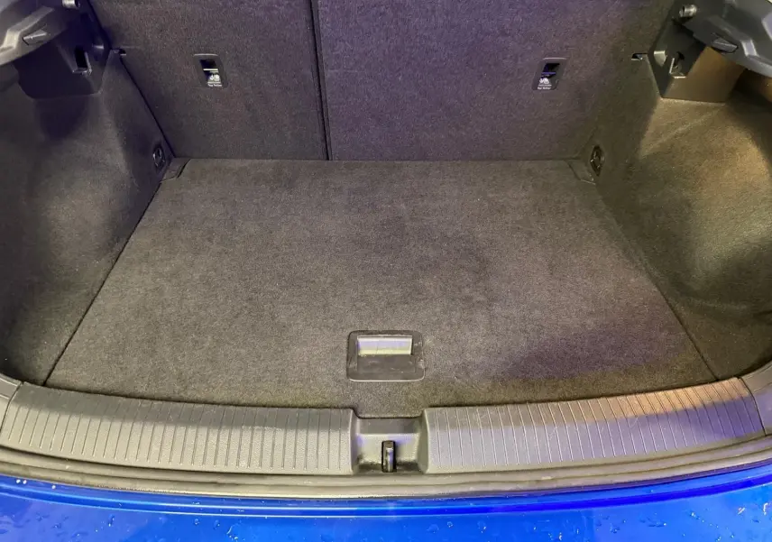 Coffre ouvert vu de face du Volkswagen T-Roc bleu, montrant un espace de chargement propre et tapis de sol noir.