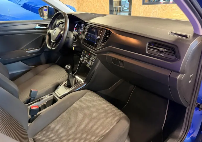 Intérieur avant droit du Volkswagen T-Roc bleu 2019, volant cuir, levier de vitesse manuel et tableau de bord moderne.