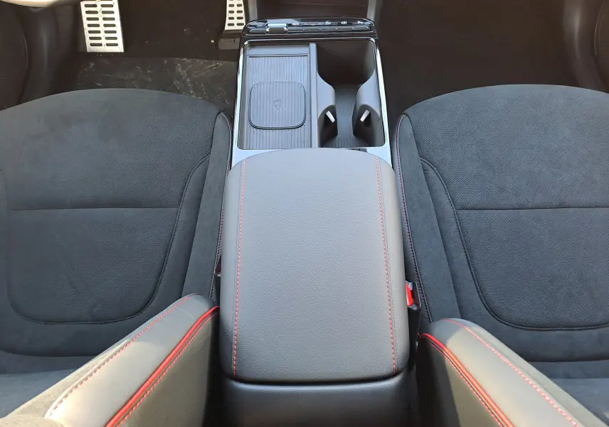 Vue plongeante sur la console centrale et les sièges noirs avec surpiqûres rouges du Hyundai Tucson 2025 hybride.