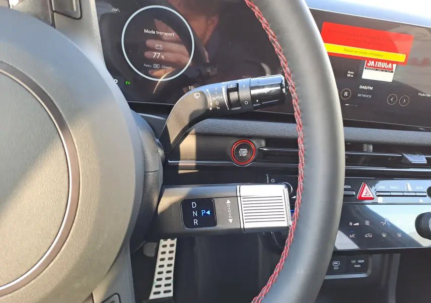 Vue intérieure du tableau de bord du Hyundai Tucson 2025 en Abyss Black, avec volant cuir noir à surpiqûres rouges et bouton start/stop rouge.