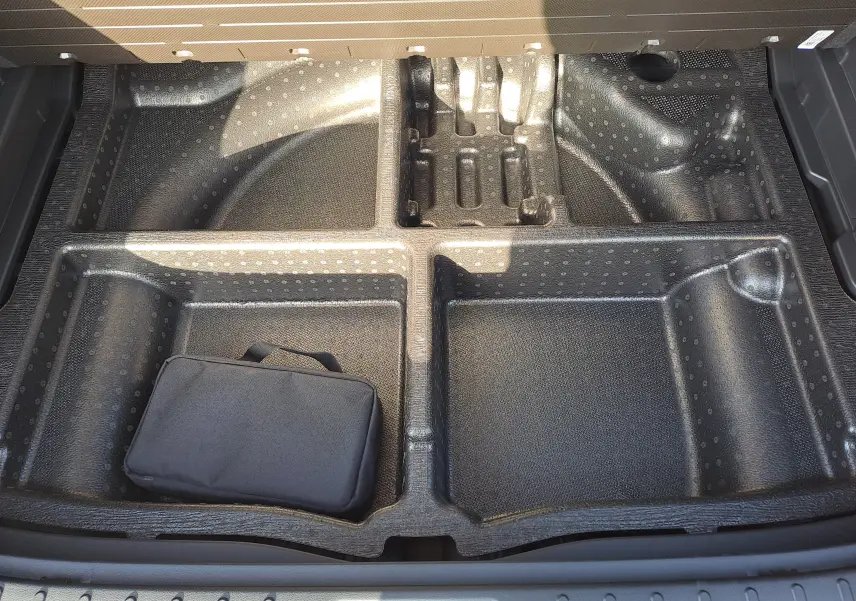 Rangement sous le coffre du Hyundai Tucson 2025 en Abyss Black, compartiments modulables avec trousse noire visible.