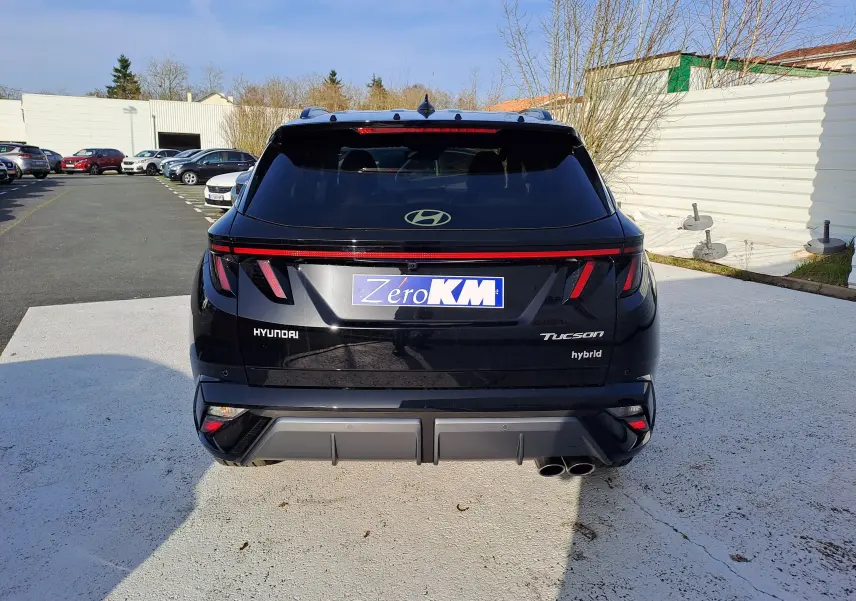 Vue arrière d'un Hyundai Tucson 2025 hybride en noir Abyss, avec feux arrière LED et double sortie d'échappement visible.