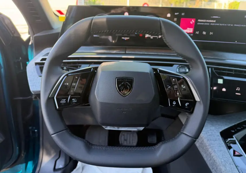 Vue rapprochée du volant cuir noir du Peugeot 3008 Hybrid 145 e-DCS6 Allure bleu 2025 avec commandes intégrées.