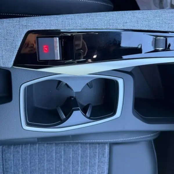 Vue rapprochée de la console centrale du Peugeot 3008 Hybrid 145 e-DCS6 Allure 2025, avec porte-gobelets et frein à main électronique.