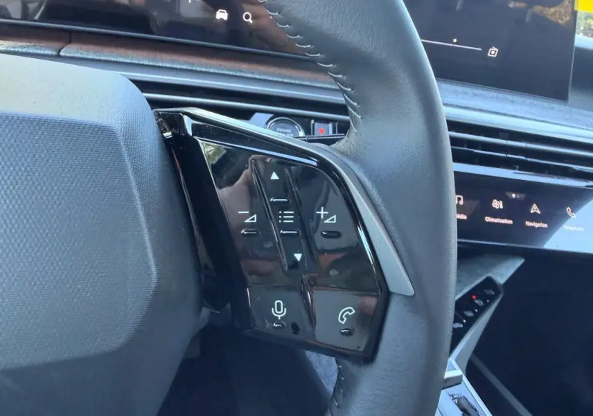 Gros plan sur les commandes gauche du volant du Peugeot 3008 Hybrid 145 e-DCS6 Allure 2025, intérieur noir moderne.