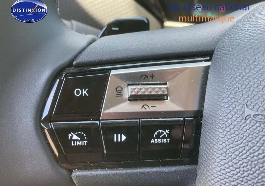 Gros plan sur les commandes au volant de la DS4 E-tense 225 gris platinium, mettant en valeur les fonctions limiteur et assist.