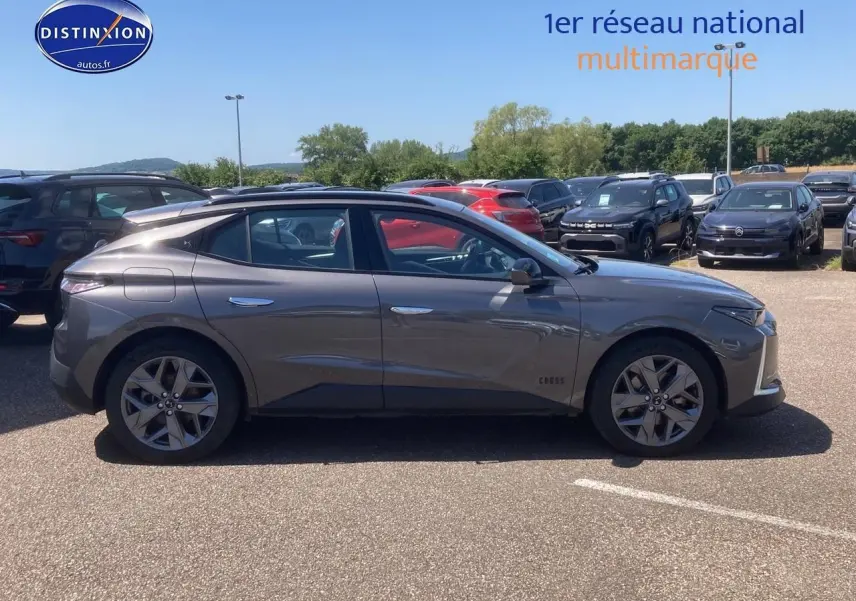 Profil côté gauche du DS4 E-tense 225 Cross Trocadero gris platinium garé en extérieur sur parking.