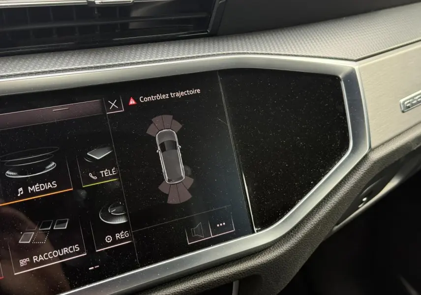 Écran tactile central de l'Audi Q3 S Line 2019 affichant l'alerte de contrôle de trajectoire, avec décor aluminium brossé.