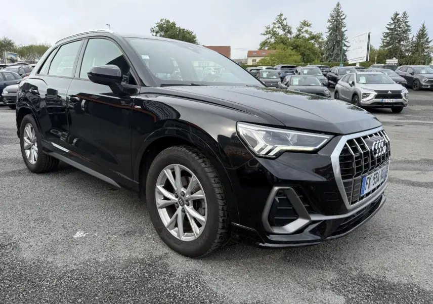 Audi Q3 noir vue 3/4 avant droit, calandre chromée et phares LED distinctifs sur parking extérieur.