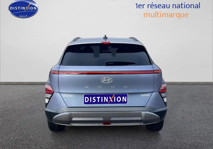 Vue arrière d'un Hyundai Kona bleu 2025 avec bande lumineuse LED et logo hybride visible sur le hayon.