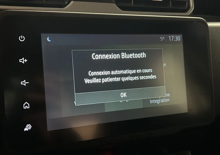 Écran tactile central du Dacia Duster 2023 affichant une connexion Bluetooth en cours, avec commandes tactiles sur le côté gauche.