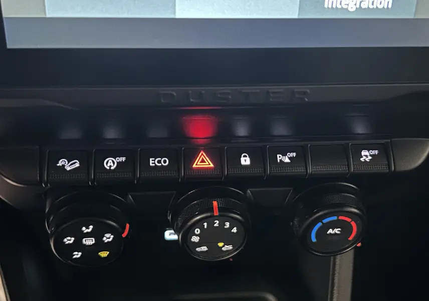Détail du tableau de bord du Dacia Duster 2023 montrant les commandes de climatisation et les boutons de fonction en noir.