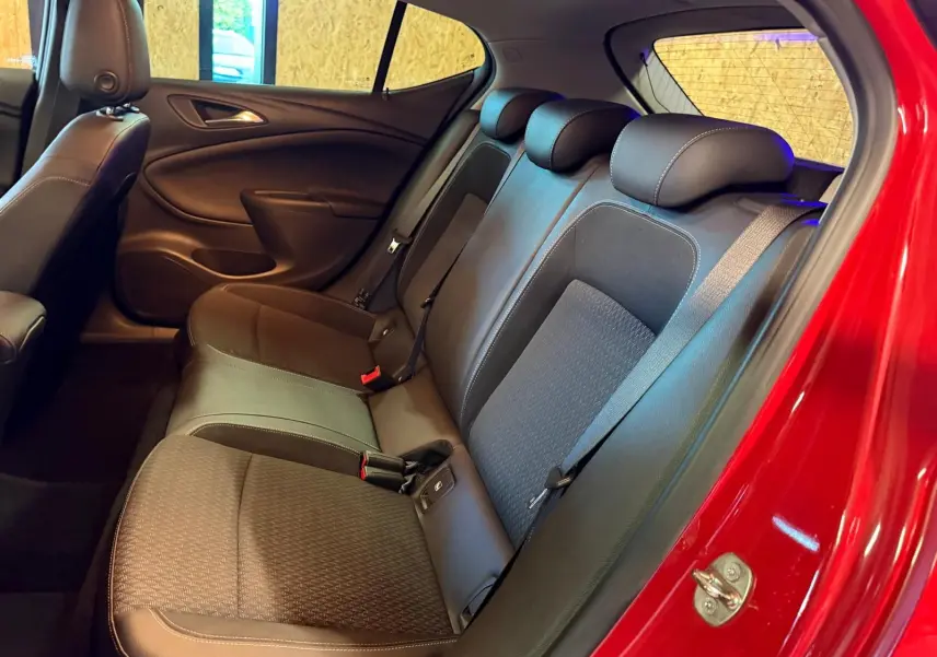 Vue intérieure côté droit arrière de l’Opel Astra rouge, montrant la banquette arrière en tissu et cuir avec appuis-têtes.