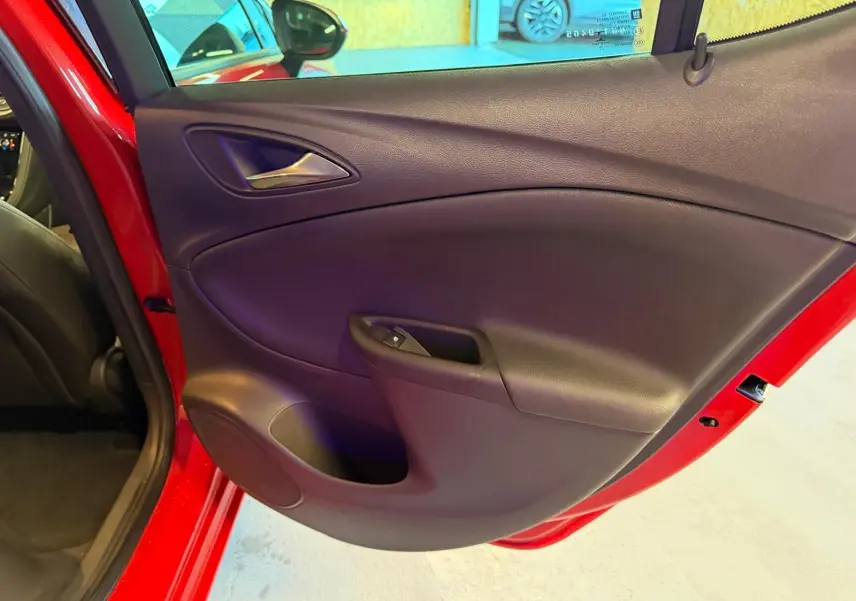 Vue intérieure de la porte arrière gauche rouge d'une Opel Astra 2016 avec commande de vitre électrique.
