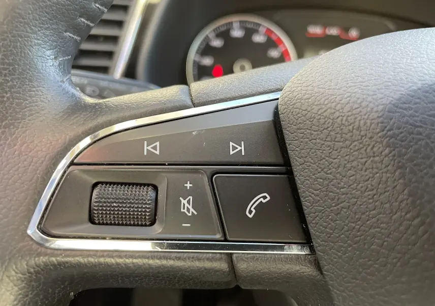 Gros plan sur les commandes audio et téléphone au volant en cuir noir du SEAT LEON ST gris 2013.