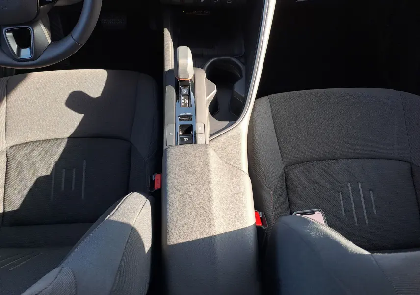 Vue plongeante sur l'intérieur du Toyota C-HR gris minéral, montrant la console centrale et les sièges avant en tissu noir.
