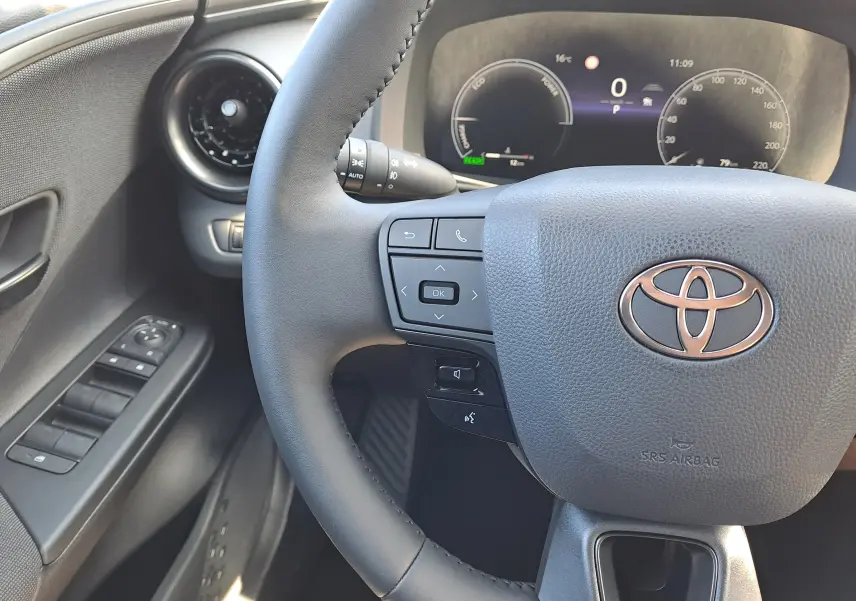 Vue rapprochée du volant et du tableau de bord numérique d'un Toyota C-HR gris minéral, version hybride 2025.