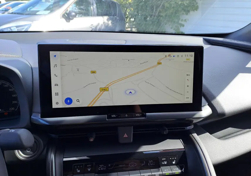 Vue intérieure du tableau de bord du Toyota C-HR gris minéral 2025, avec écran tactile central affichant la navigation.