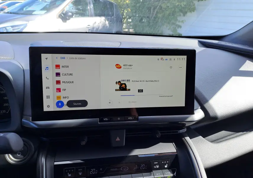 Écran tactile central du tableau de bord du Toyota C-HR gris minéral 2025, affichant la radio DAB et commandes climatisation.