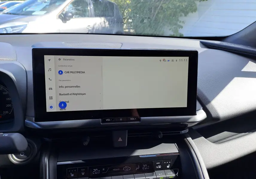 Écran tactile central du tableau de bord du Toyota C-HR gris minéral, affichant le menu multimédia en extérieur lumineux.