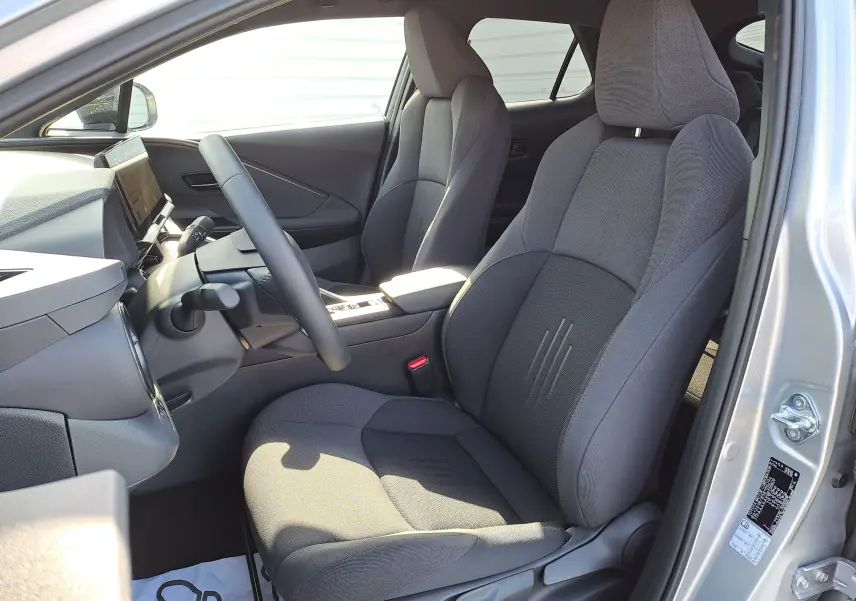 Vue intérieure côté conducteur du Toyota C-HR gris minéral 2025, sièges tissu gris et tableau de bord moderne.