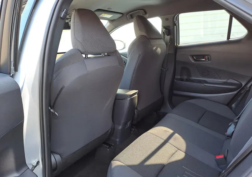 Vue intérieure arrière droite du Toyota C-HR gris minéral 2025, montrant les sièges arrière et le dossier des sièges avant en tissu noir.