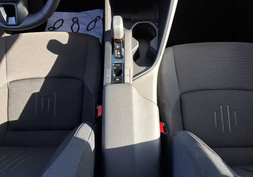 Vue plongeante sur la console centrale et les sièges avant noirs du Toyota C-HR gris minéral 2025 hybride avec boîte auto.