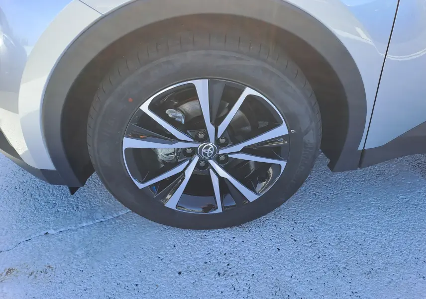 Gros plan sur la roue avant droite du Toyota C-HR gris minéral avec jante alliage bicolore 18 pouces.
