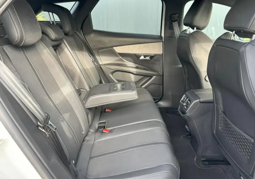 Vue intérieure côté gauche des sièges arrière du Peugeot 3008 2024 en cuir noir avec accoudoir central rabattable.