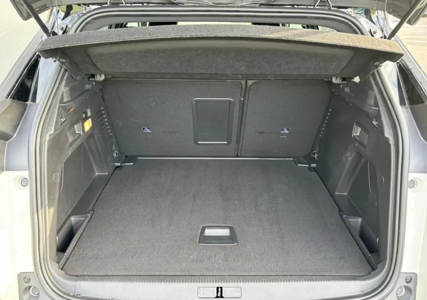 Coffre ouvert vu de l'arrière d'un Peugeot 3008 blanc nacré, montrant un espace de chargement propre et spacieux.