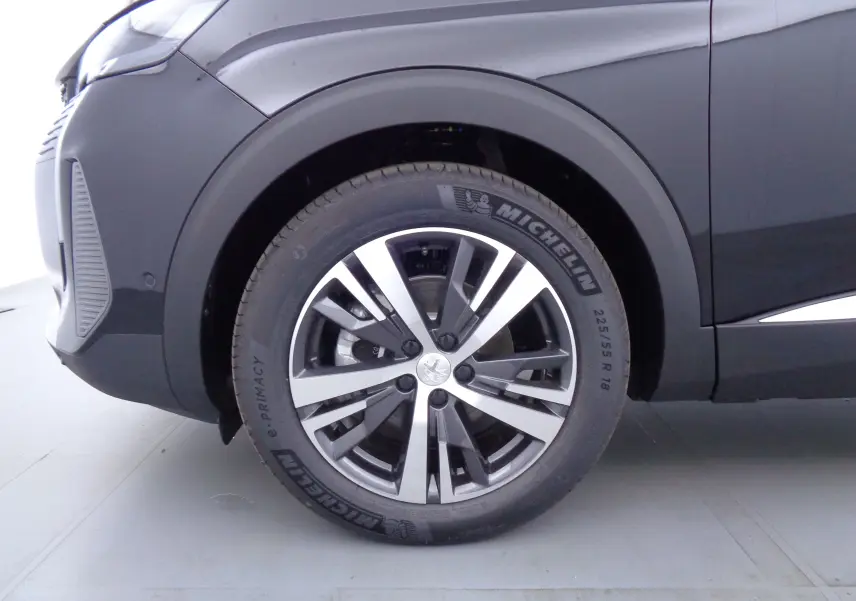 Gros plan sur la roue avant gauche du Peugeot 3008 noir Perla Nera 2023 avec jante alliage bicolore.