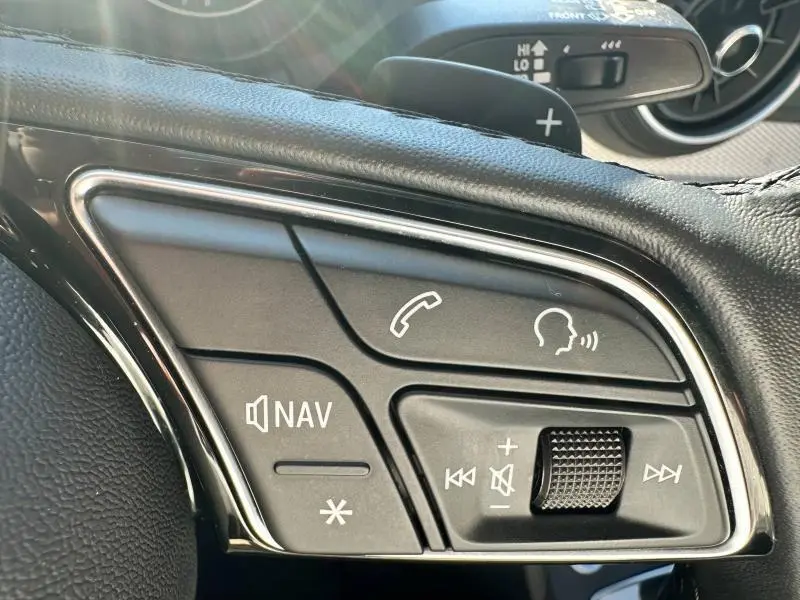 Gros plan sur les commandes au volant du Audi Q2 35 TFSI S line 2023 en Noir Mythic métallisé, boutons de navigation et audio visibles.