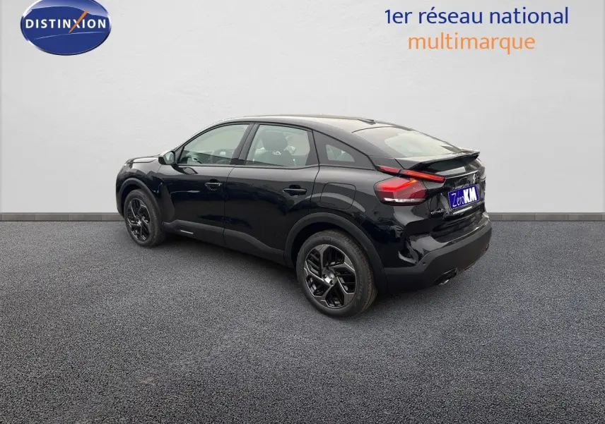 Vue 3/4 arrière droite d'une Citroën C4 noire métal 2024 avec jantes noires et feux arrière LED distinctifs.