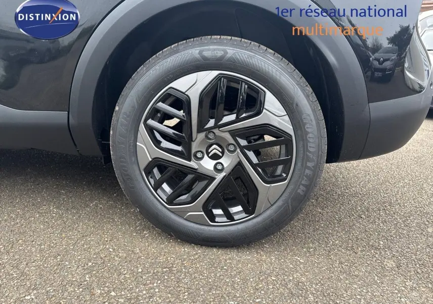 Gros plan sur la roue avant gauche noire métal d'une Citroën C4 2024 avec jante biton stylisée et logo Citroën central.