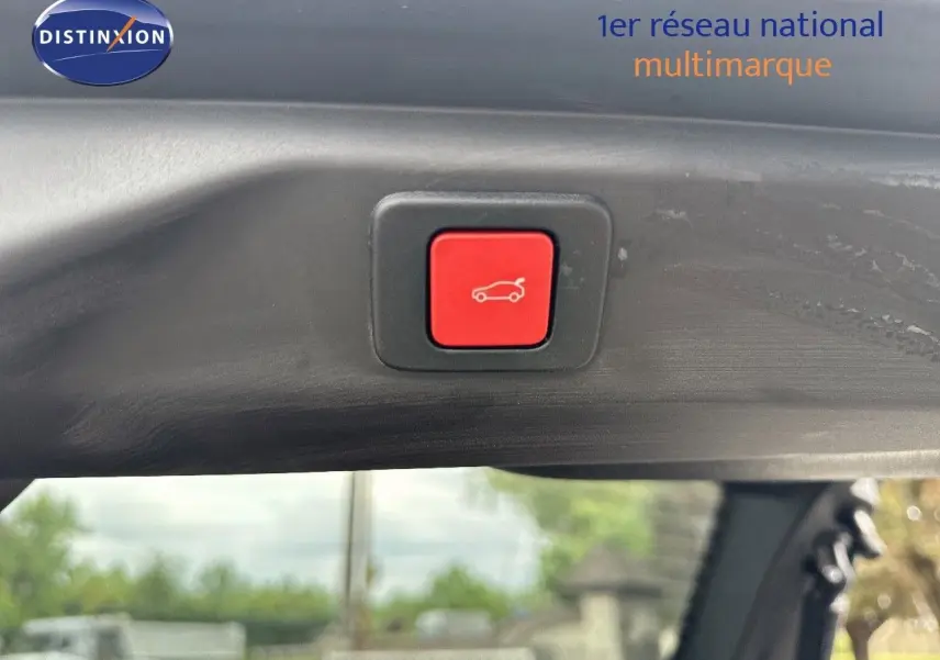 Bouton rouge d'ouverture électrique du hayon sur le bord intérieur d'un Peugeot 3008 Hybrid bleu Ingaro métal avec toit noir.