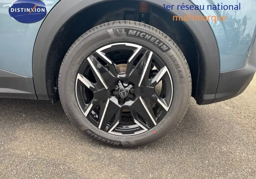 Gros plan sur la roue avant droite du Peugeot 3008 Hybrid 136ch GT bleu Ingara métal avec jante noire et argentée.