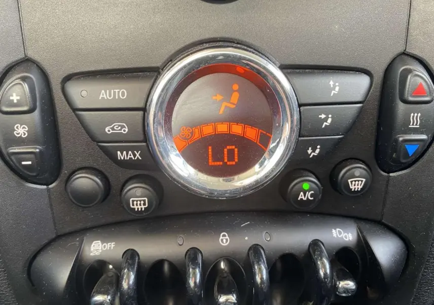 Gros plan sur la commande de climatisation automatique du MINI Countryman gris clair, affichage digital orange indiquant "LO".