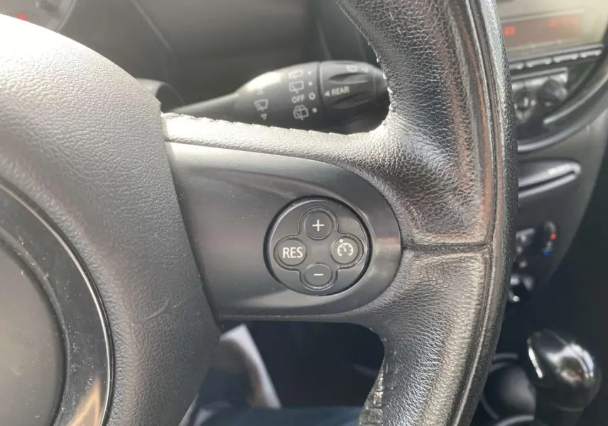 Gros plan sur le volant en cuir noir du MINI Countryman gris clair, avec commandes de régulateur de vitesse visibles.