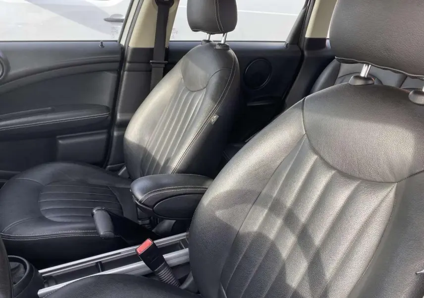 Vue rapprochée des sièges avant en cuir noir d'une MINI Countryman 2015, soulignant le détail des coutures et l'accoudoir central.