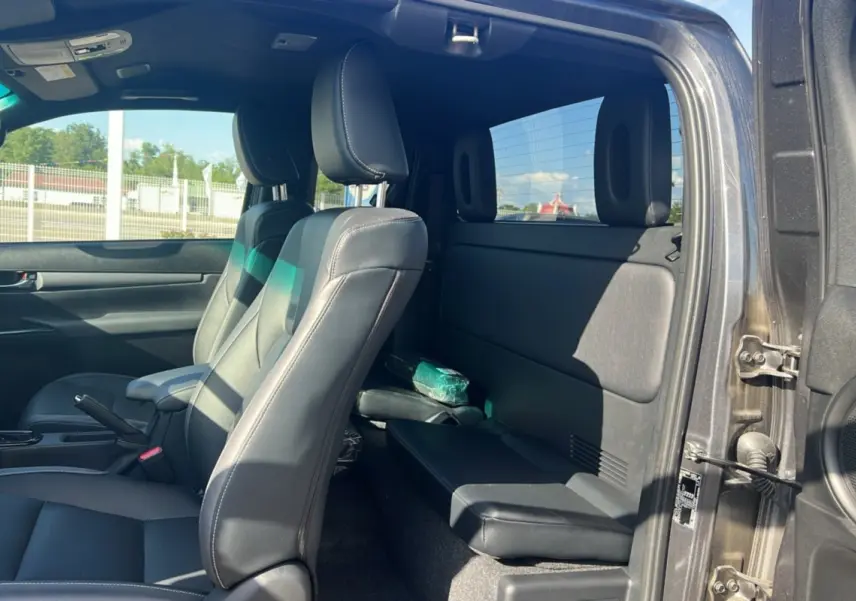 Intérieur du Toyota Hilux 2025 gris atlas, vue côté droit sur les sièges avant en cuir et banquette arrière compacte.