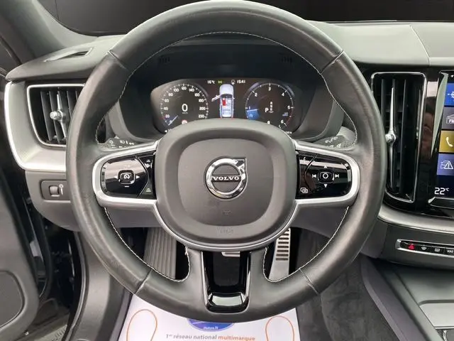 Vue centrée sur le volant cuir noir du Volvo XC60 2021 avec tableau de bord digital et commandes intégrées.