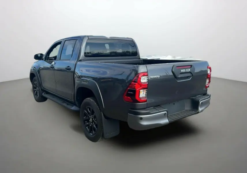 Toyota Hilux 4x4 gris atlas en 3/4 arrière droit, avec benne ouverte et jantes noires distinctives.